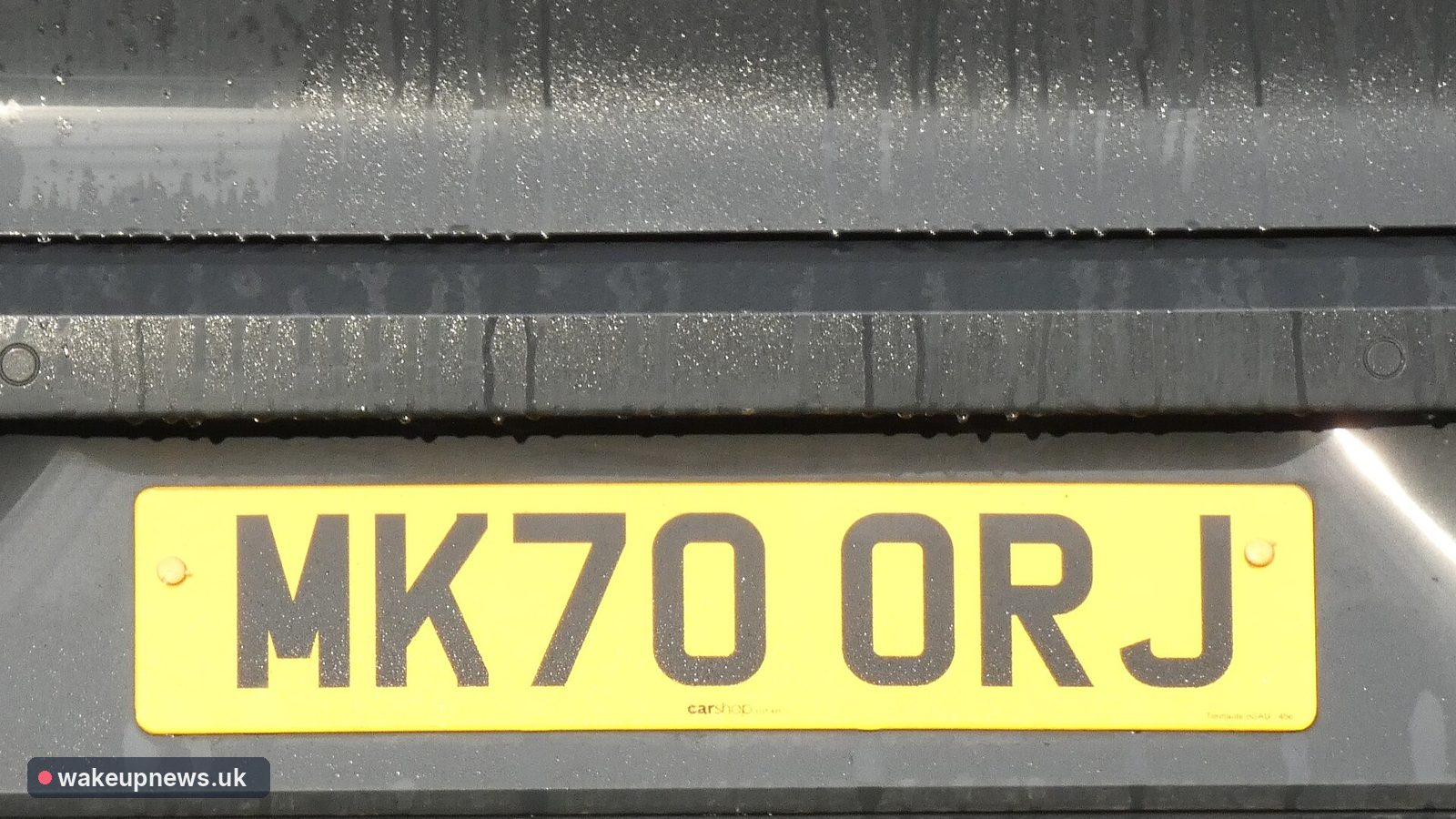Yellow UK rear number plate reading MK70 ORJ on a grey car