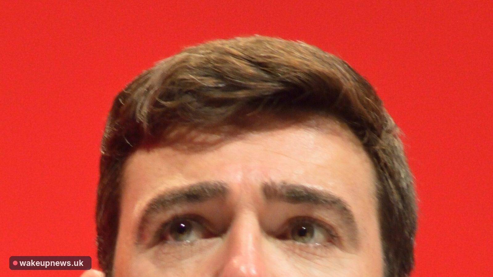 Close-up of Andy Burnham's face against a red background