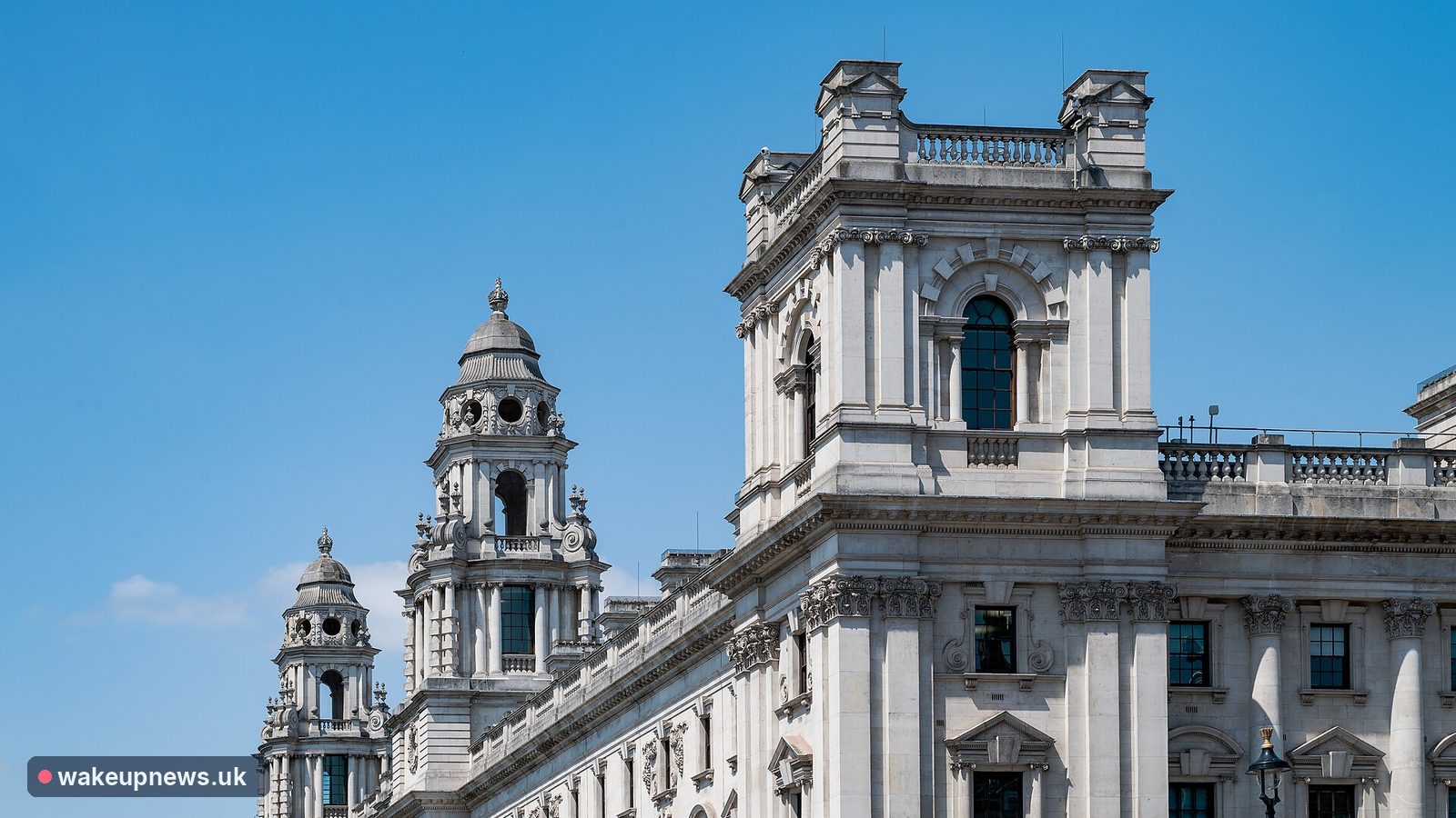Ornate stone towers of the HM Treasury building in Whitehall under a blue sky