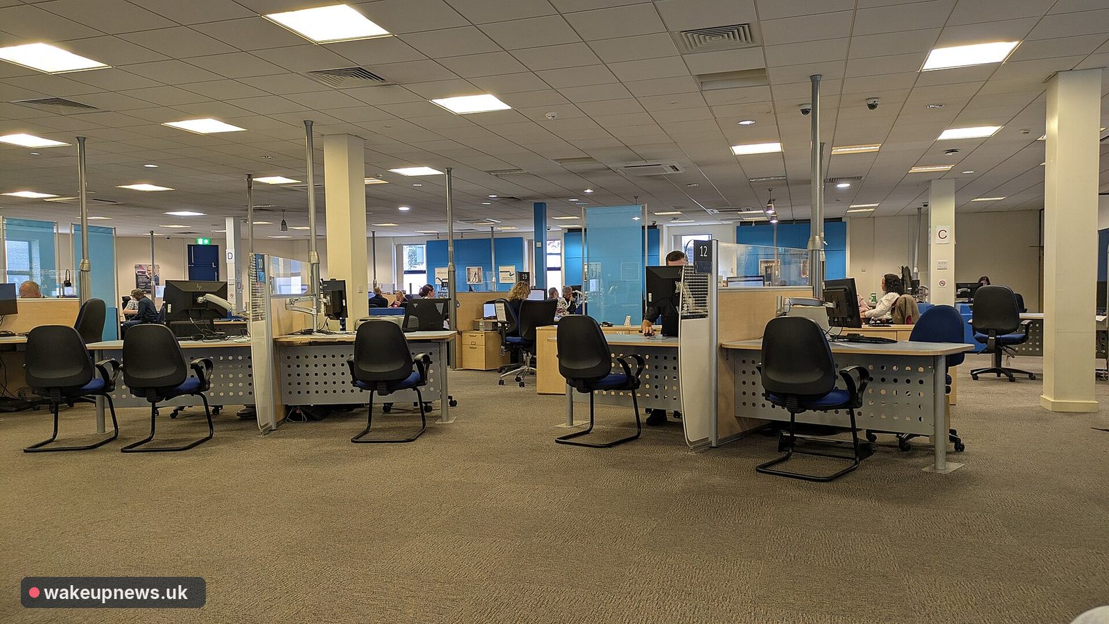 Inside a Jobcentre Plus office, with rows of desks, computers and empty chairs