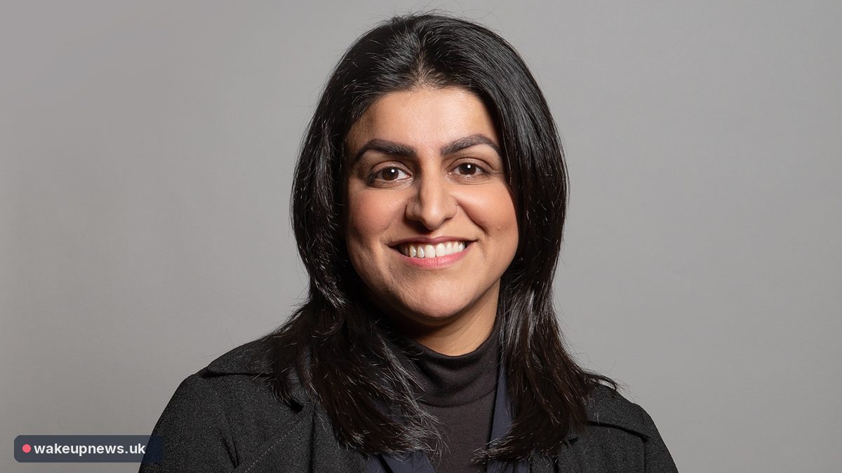 Home Secretary Shabana Mahmood smiling in a dark jacket against a grey background