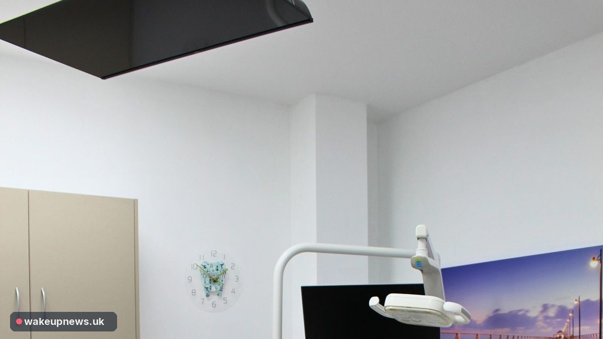 Modern dental surgery room with an overhead dental lamp, a monitor and white cabinets
