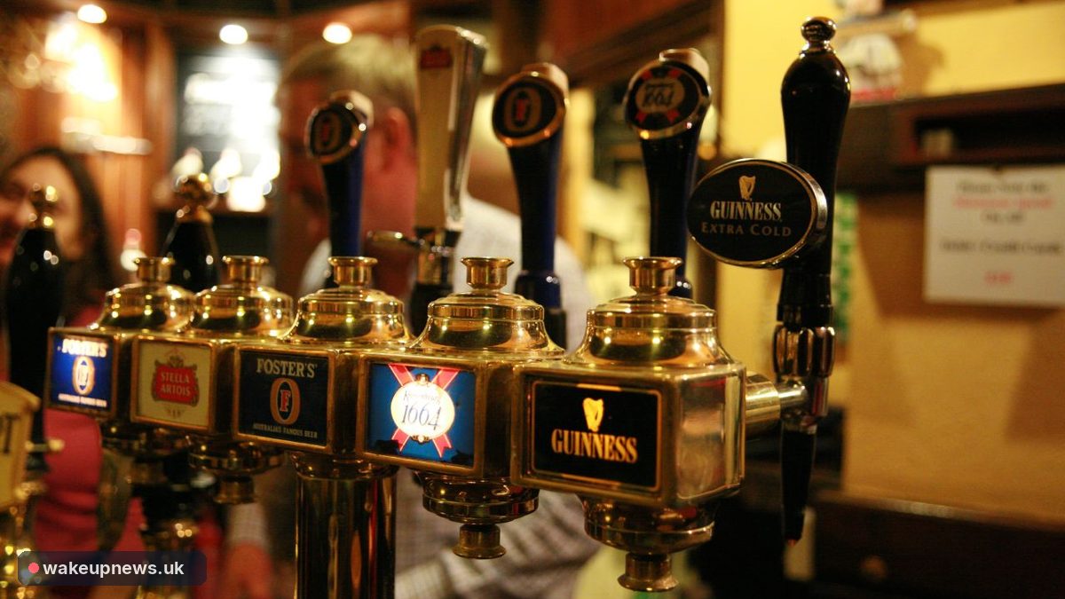 Row of brass beer taps, including Guinness and Foster's, on a pub bar